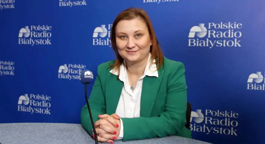Wiceminister edukacji w zielonej marynarce udziela wywiadu w Polskim Radiu Białystok.