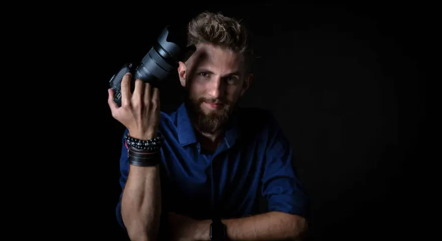 Mężczyzna z aparatem fotograficznym, gotowy do rozpoczęcia kursu fotografii.