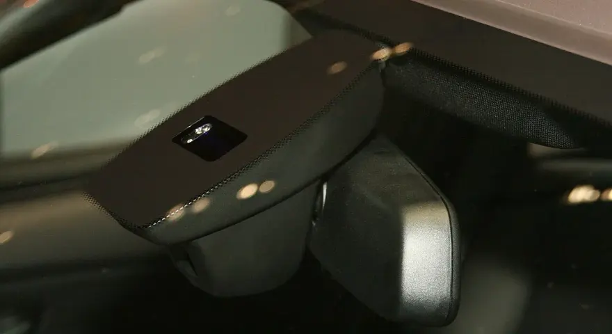 Nahaufnahme eines Regensensors im Auto, der die Windschutzscheibe überwacht, um bei Regen die Scheibenwischer zu aktivieren.