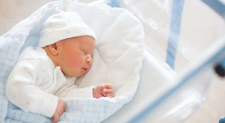 Śpiący noworodek w czepku z napisem "DADDY". To idealny moment na becikowe dla kogoś tak małego.