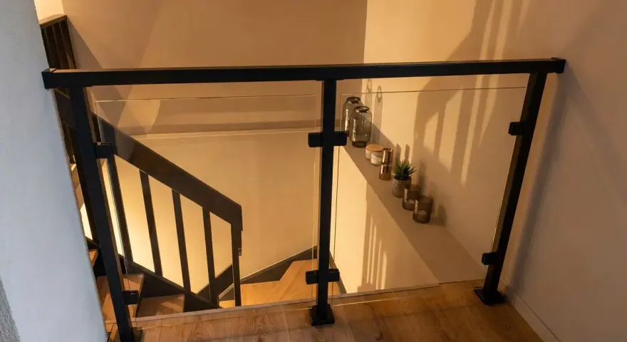 Nowoczesna balustrada ze szkła i czarnego profilu, idealna do schodów. Pokazuje, jak zrobić balustradę z profila.