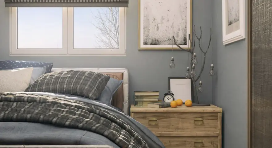Ideas para decorar una habitación: cama con textiles grises, mesita de noche de madera con adornos y cuadros en la pared.