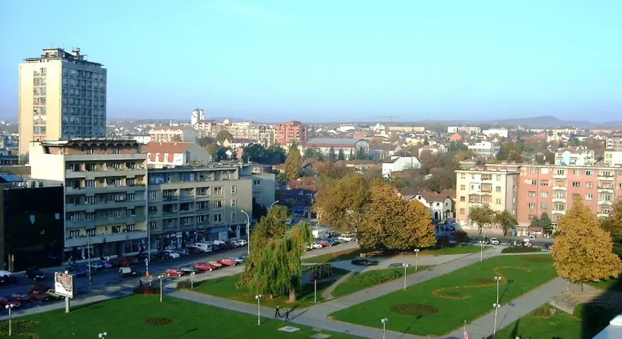 Widok na centrum Kragujevac Serbia z budynkami mieszkalnymi, parkiem i ulicą pełną samochodów.