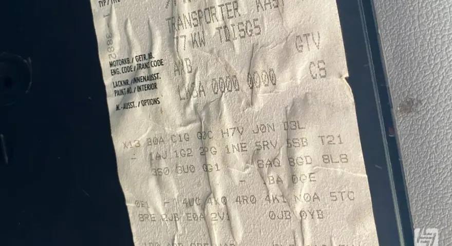 Aufkleber mit Fahrzeugdaten, um die PR-Nummern zu entschlüsseln. Zeigt Transporter, Motorcode AXB, Lacknummer und Optionen.
