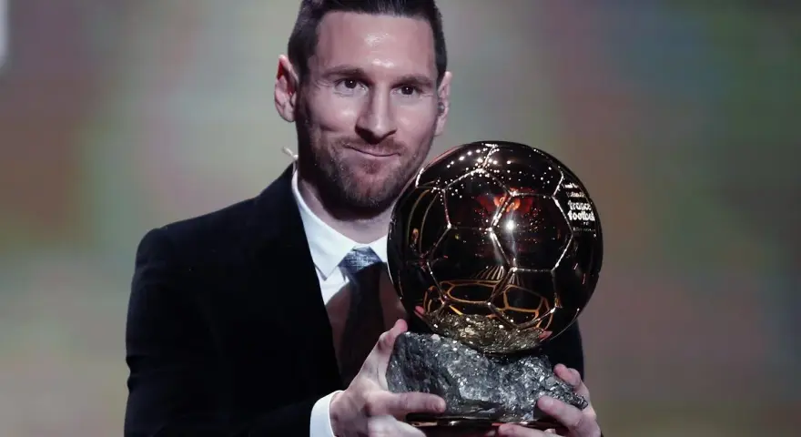 Lionel Messi, który dostał Złotą Piłkę, prezentuje trofeum.