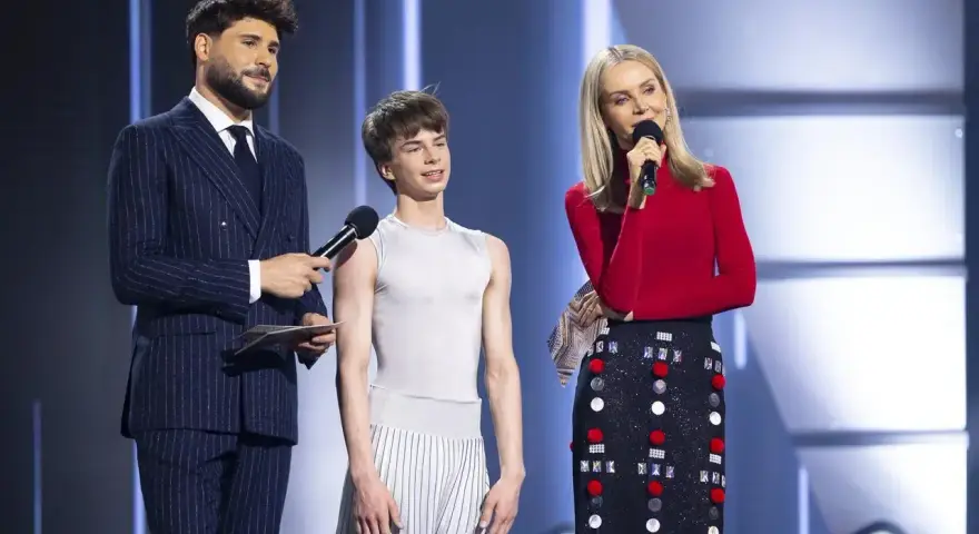 Tymek Sobczyk w białej koszulce i spodniach w paski, obok prowadzących program.