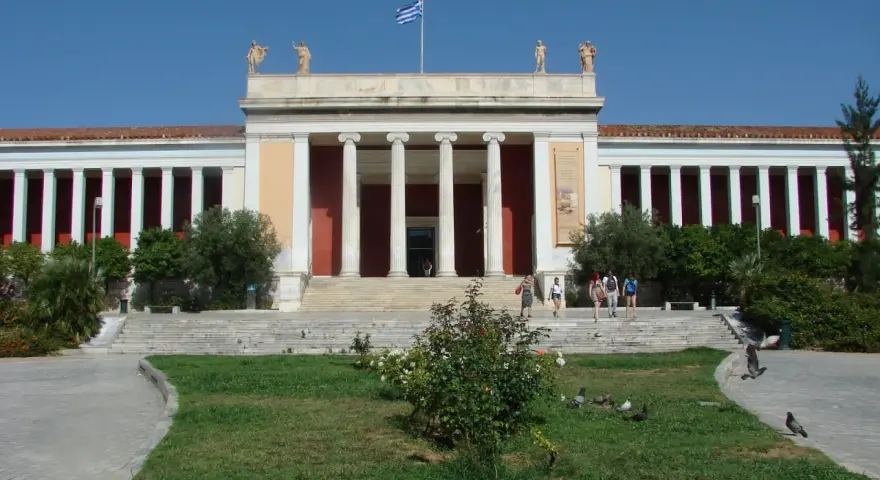 Narodowe Muzeum Archeologiczne w Atenach, z grecką flagą na dachu, zaprasza zwiedzających.