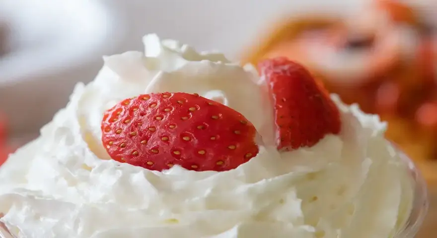 Chantilly aérienne garnie de fraises fraîches. Une invitation à découvrir comment faire de la chantilly maison pour un dessert parfait.
