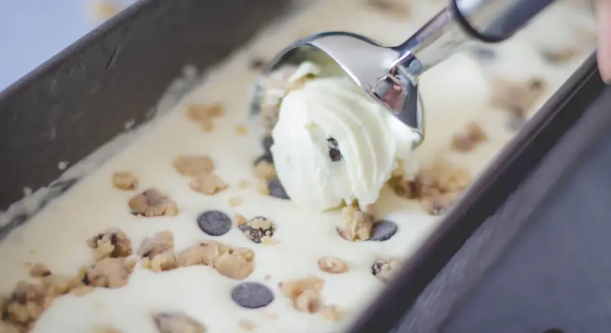 Mit einem Eisportionierer wird cremiges Cookie Dough Eis mit Schokostückchen aus einer Form gehoben. Perfekt, um Eis selber machen zu erleben!