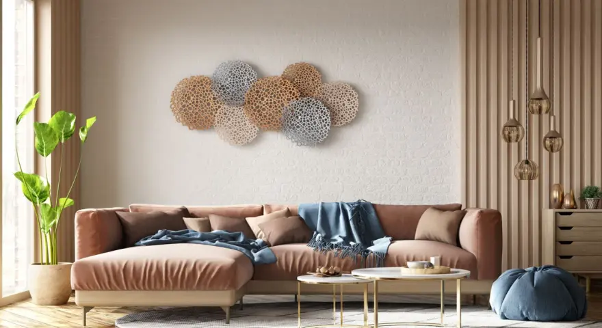 Decoración pared salón original con un sofá terracota y arte de pared circular en tonos dorados y plateados.