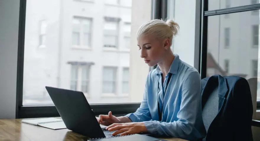 Donna bionda lavora al laptop, analizzando dati per ottimizzare lo stipendio dell'e-commerce manager.