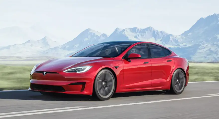 Czerwony Tesla Model S jedzie po drodze, a w tle widać góry. Tesla co to? To przyszłość motoryzacji.