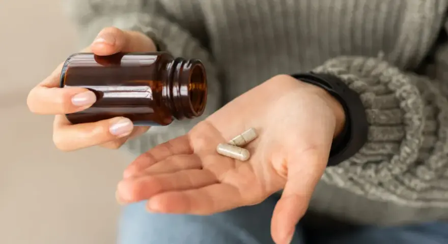 Dłoń z kapsułkami, zastanawiam się nad biotyna skutki uboczne.