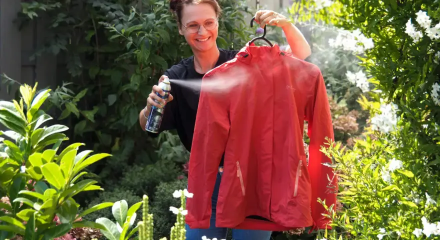 Frau sprüht rote Funktionskleidung ein, um sie für das Waschen vorzubereiten.