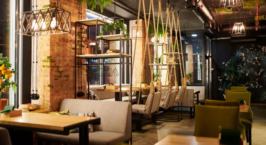 Un restaurante moderno con ladrillo visto, plantas colgantes y columpios. Un lugar acogedor que inspira lo que se necesita para abrir un restaurante.