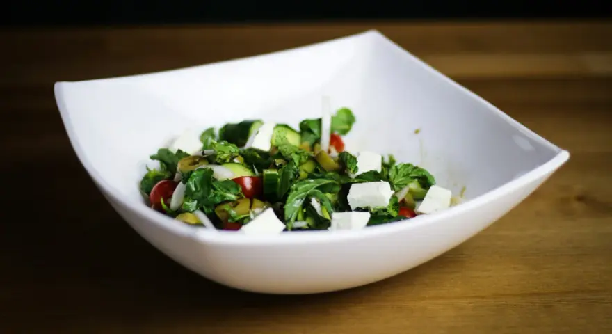 Salade fraîche et colorée avec des cubes de fromage pour salade, tomates cerises, concombres et olives vertes.