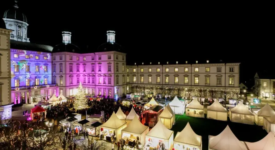 Einzigartiger Weihnachtsmarkt Bensberg vor beleuchtetem Schloss. Viele Stände und ein großer Weihnachtsbaum laden zum Bummeln ein.