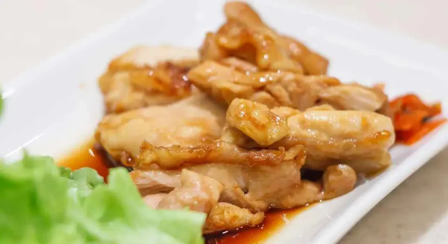 Straccetti di pollo succulenti in salsa agrodolce, serviti con insalata fresca e carote.