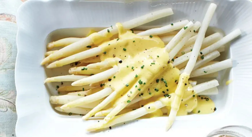 Asperges blanches nappées d'une sauce onctueuse, parsemées de ciboulette fraîche. Un délice printanier.