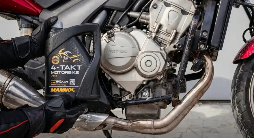 Rękawice motocyklisty trzymają olej Mannol 4-Takt Motorbike SAE 10W-40. Jaki olej do motocykla? Ten zapewni płynną pracę silnika Honda.