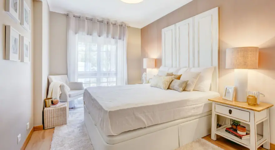Camera da letto accogliente con letto bianco, comodino con libri e lampada. Idee su cosa mettere su como camera da letto.