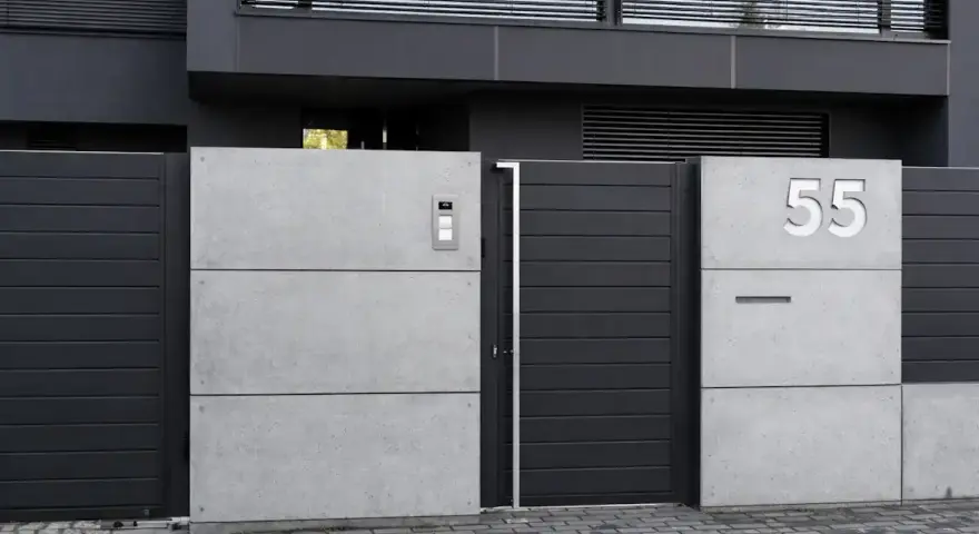 Nowoczesne ogrodzenie domu z betonowych płyt i ciemnoszarych paneli. Elegancki pomysł na ogrodzenie domu z numerem 55.