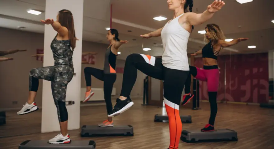 Kobiety na stepach wykonują trening aerobowy co to jest, ćwicząc równowagę i kondycję.