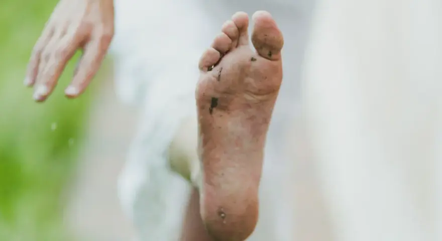 Pie sucio y descalzo, con tierra y hierba. Un consejo para como quitar el olor de los pies es lavarlos bien.
