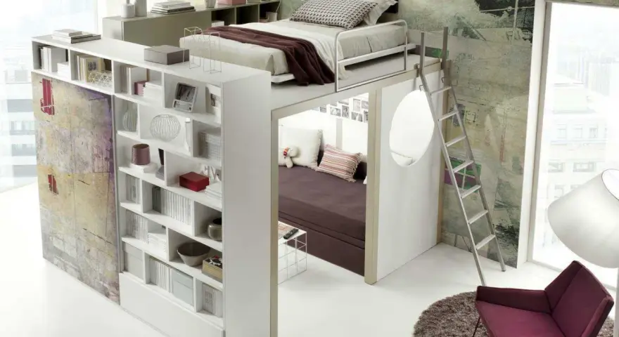 Arredamenti camerette moderni: letto soppalcato con libreria integrata e zona relax sottostante, scala a pioli, poltrona e tappeto.