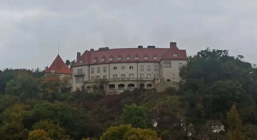 Zamek na wzgórzu, otoczony jesiennym lasem, przypomina o historii Krakowa i Kalwarii Zebrzydowskiej.