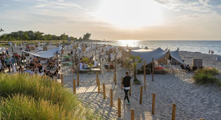Sommerliche Ostsee Party mit vielen Gästen, Strandkörben und Zelten am Abend.