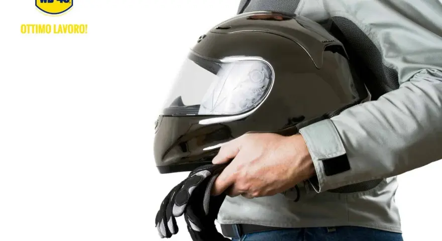 Un motociclista tiene un casco nero lucido e guanti. Scopri come pulire visiera casco per una guida sicura.