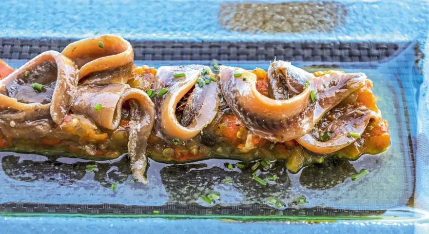 Alici sott'olio su un letto di verdure, un piatto gustoso e nutriente, perfetto anche se si possono mangiare le alici sott'olio in gravidanza.