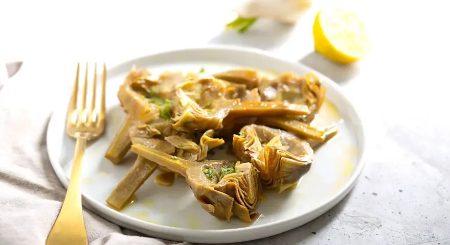 Carciofi cotti in olio e limone, pronti per essere serviti. Scopri come congelare i carciofi per averli sempre a disposizione.