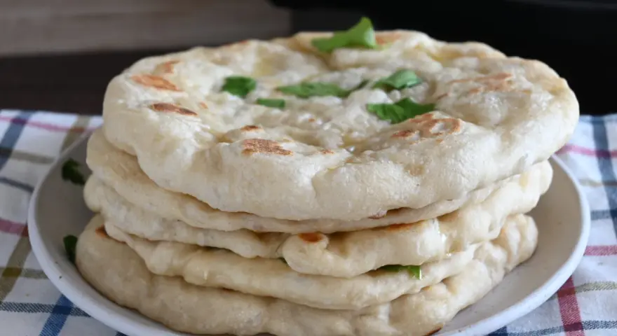 Pila di pane in padella, soffice e dorato, guarnito con erbe fresche. Perfetto per accompagnare ogni pasto.