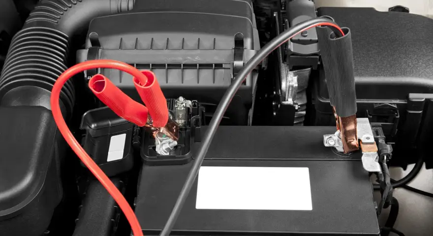 Jumper cables connected to a car battery. Learn how long to leave jumper cables on for a successful jump start.