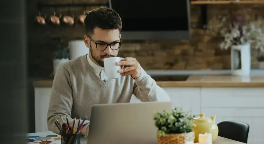 Homme buvant un café devant son ordinateur, pensant à son indemnité transactionnelle CSG CRDS.