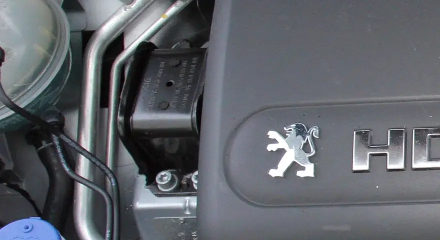 Widoczna uszkodzona poduszka silnika w samochodzie Peugeot.