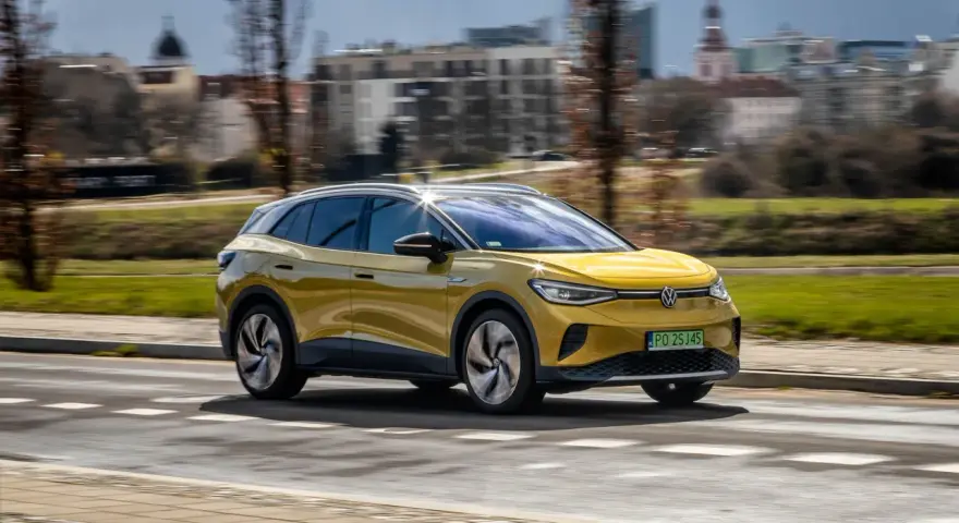 Żółty VW ID.4 jedzie po mieście, pokazując swój imponujący zasięg.