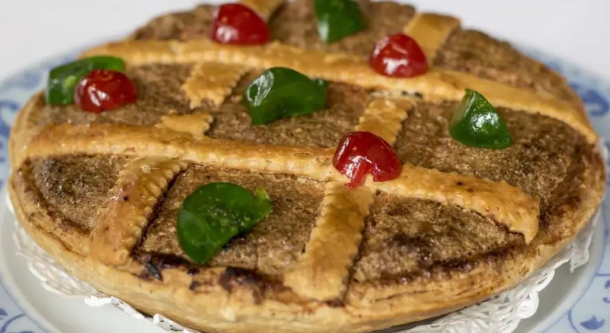 Tarta de Mondoñedo, un dulce tradicional con masa dorada, relleno de frutos secos y decorada con cerezas rojas y verdes.