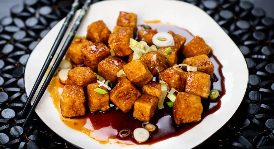 Krispiga, glaserade tofubitar med salladslök och en mörk sås. Ett läckert tofu recept som ser fantastiskt ut!