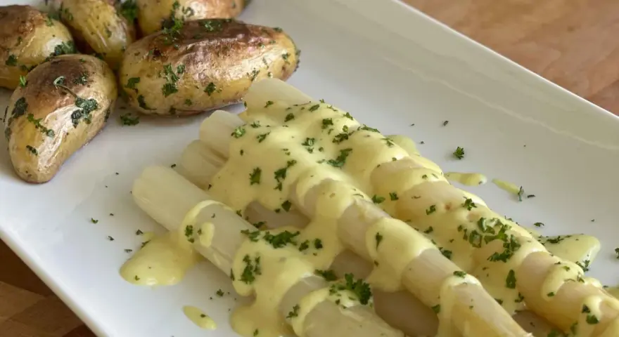 Weißer Spargel mit Kartoffeln und cremiger, veganer Hollandaise, bestreut mit frischer Petersilie. Ein Genuss!