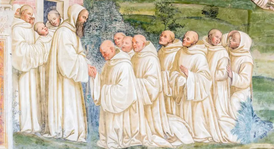 A bearded monk greets a line of novices, their white robes hinting at a rich monk history.