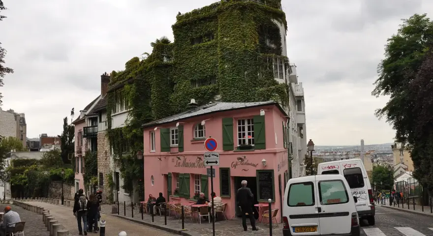 Urokliwa ulica na Montmartre z różową kawiarnią La Maison Rose i budynkiem porośniętym bluszczem.