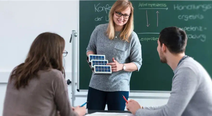 Lehrerin erklärt Schülern, wie man Berufsschullehrer wird, mit Solarzellen-Modell.