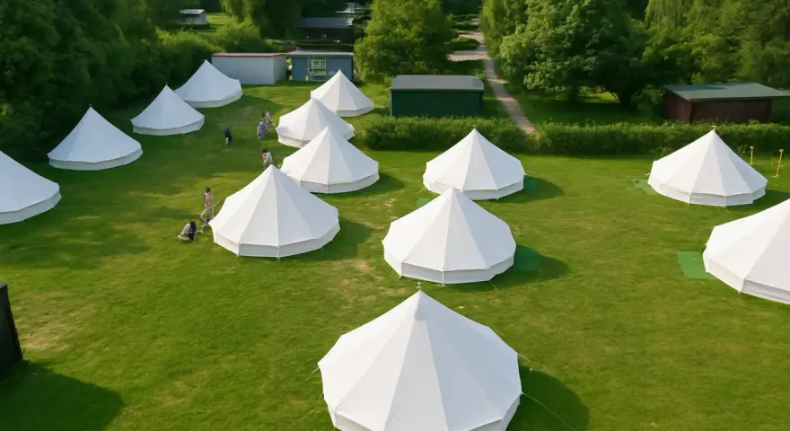 Malowniczy glamping nad morzem: białe namioty tipi na zielonej trawie, otoczone drzewami. Idealne miejsce na relaks.