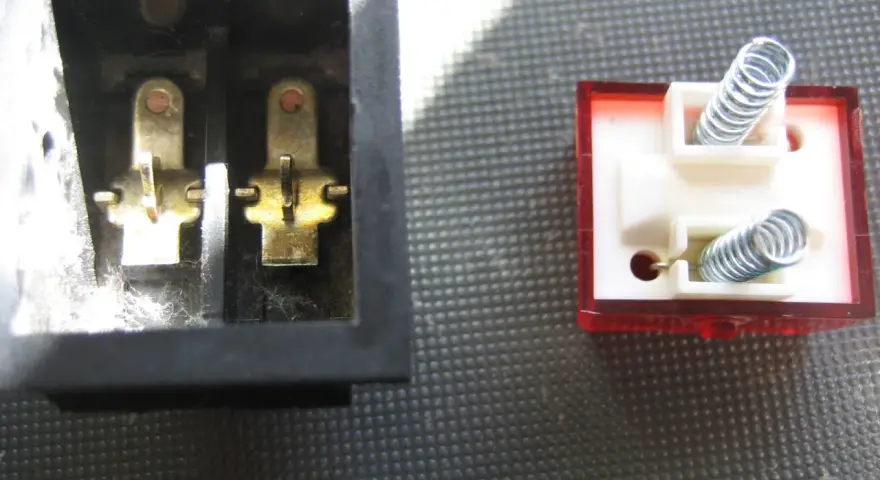 Detalle del interruptor de paso por dentro: contactos metálicos en un lado y resortes en el otro, listos para conectar.