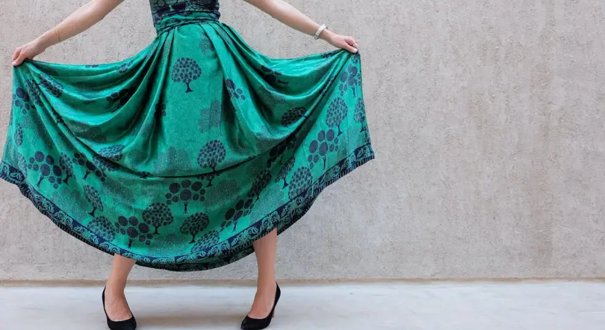 Abito color ottanio con fantasia di alberi. Scarpe nere eleganti completano il look.