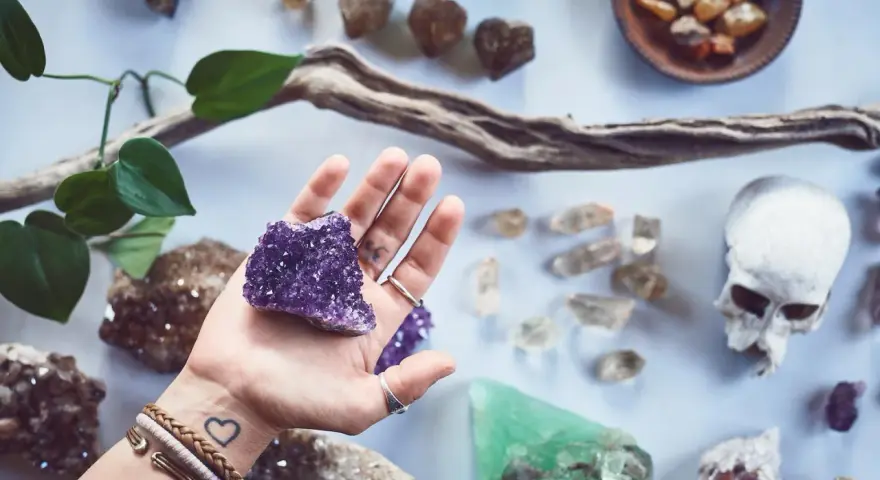 Mano sostiene amatista, rodeada de piedras y un cráneo. Un conjunto de piedras contra el mal de ojo y la envidia.