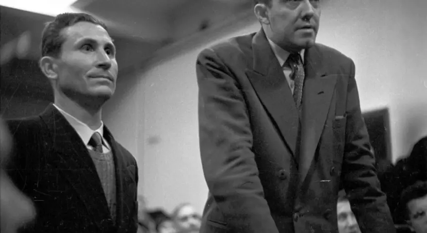 Deux hommes en costume, dont Gustave Dominici, se tiennent debout dans une salle.